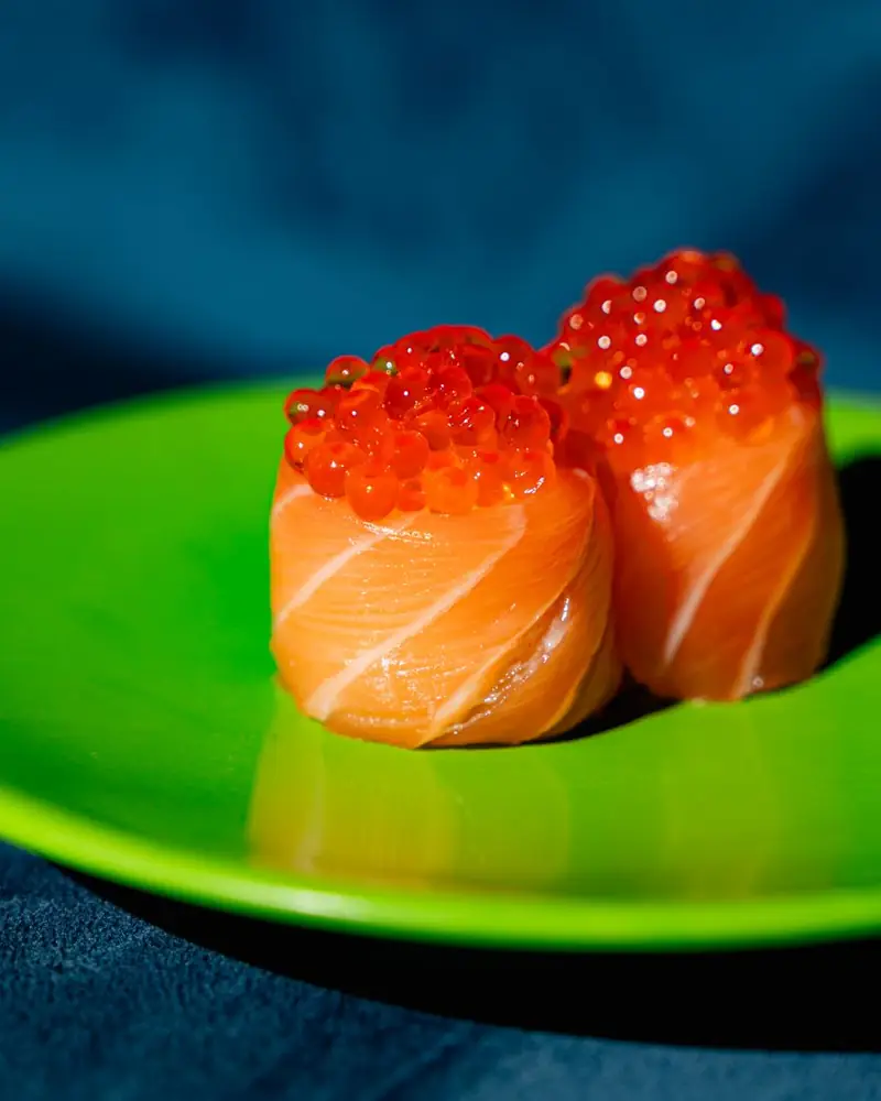 Gunkan di salmone con uova di salmone su piattino verde