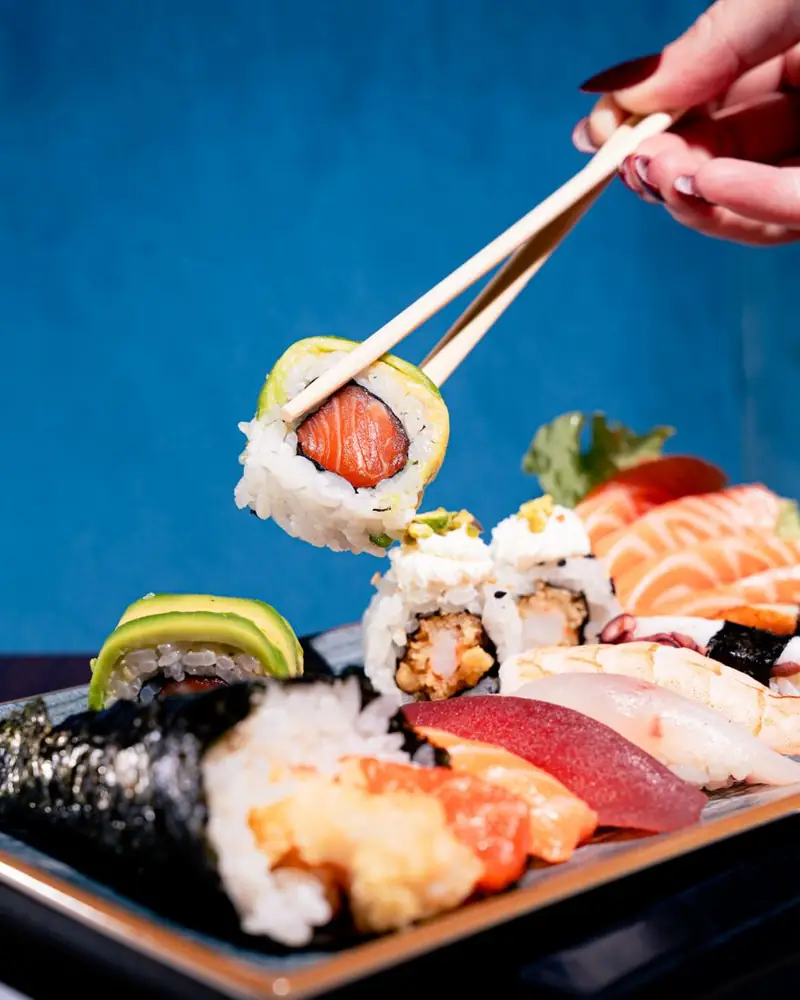 Uramaki con salmone e avocado preso con le bacchette